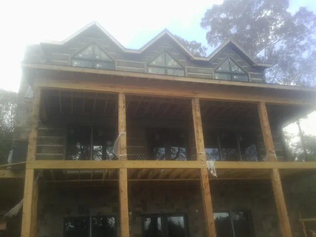 Dormers and porch framing on a large log home under construction — Roof Coating work by our crew in Boca Grande