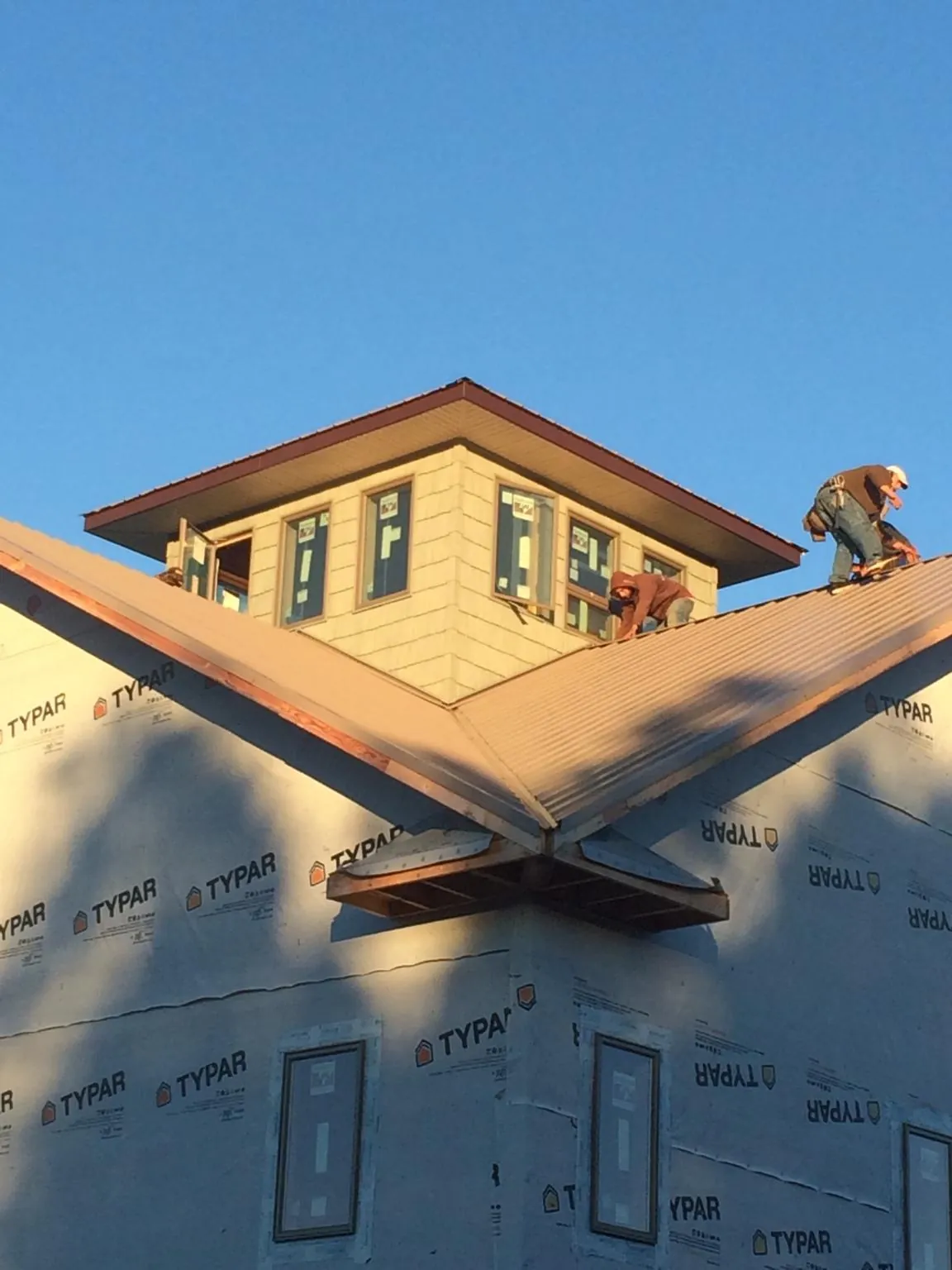 Roofers working around a rooftop cupola on a new metal roof at sunset — Roof Waterproofing in Boca Grande by Roofing Brothers